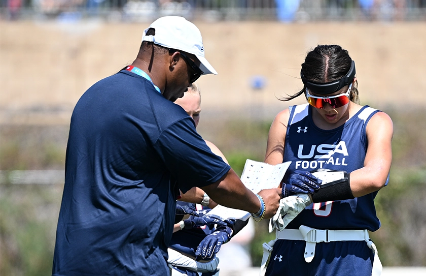 USA Football coach providing instruction to athlete during Select Bowl training session.